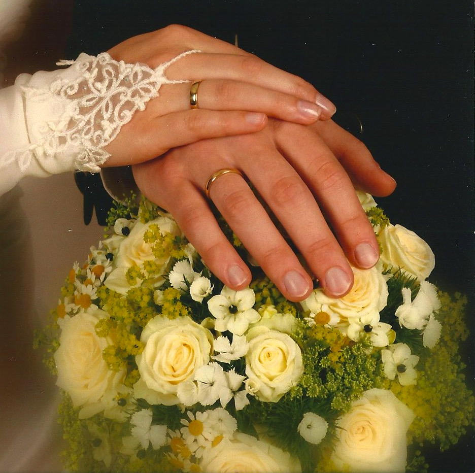 Hand eines Mannes und einer Frau mit Eheringen