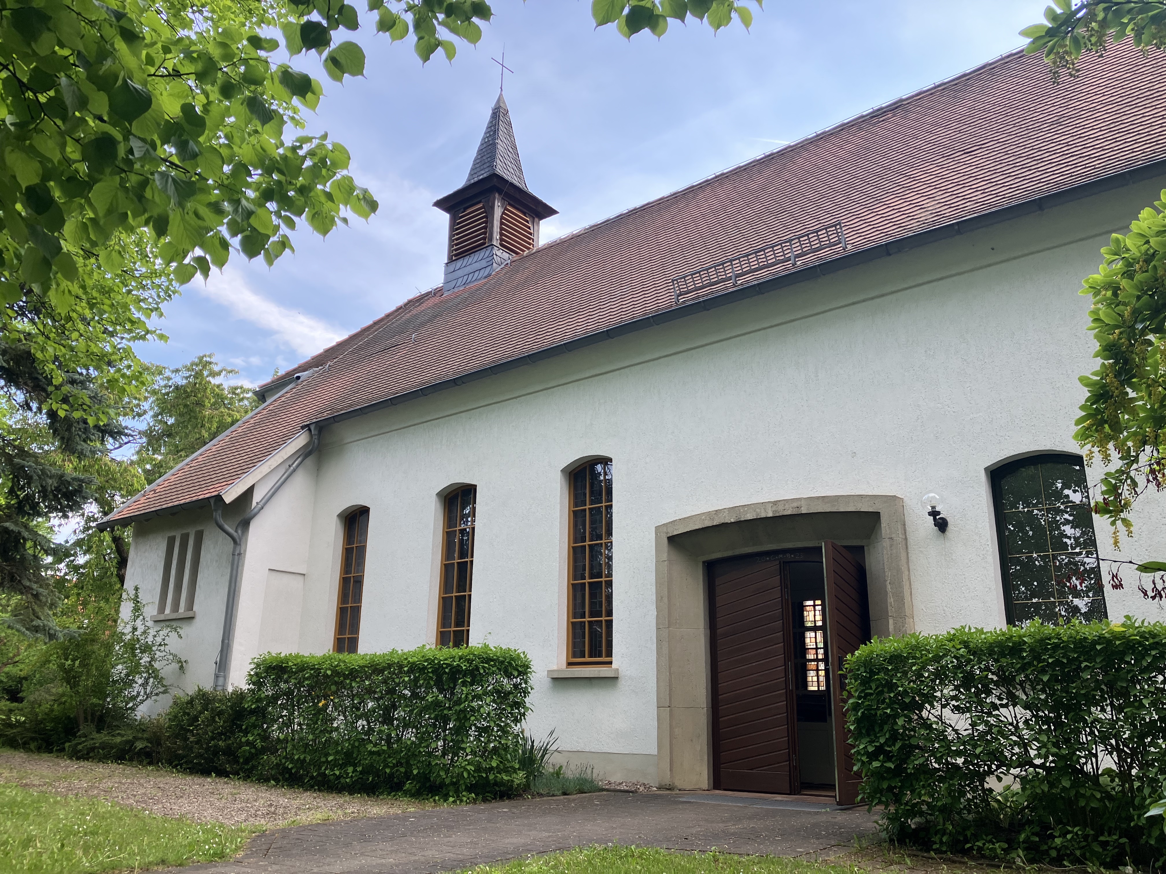 weiß gestrichene Kirche mit roten Dachziegeln und kleinem Turm, offenstehende Tür