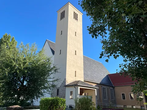 Kirchengebäude mit großem Betonturm im Vordergrund