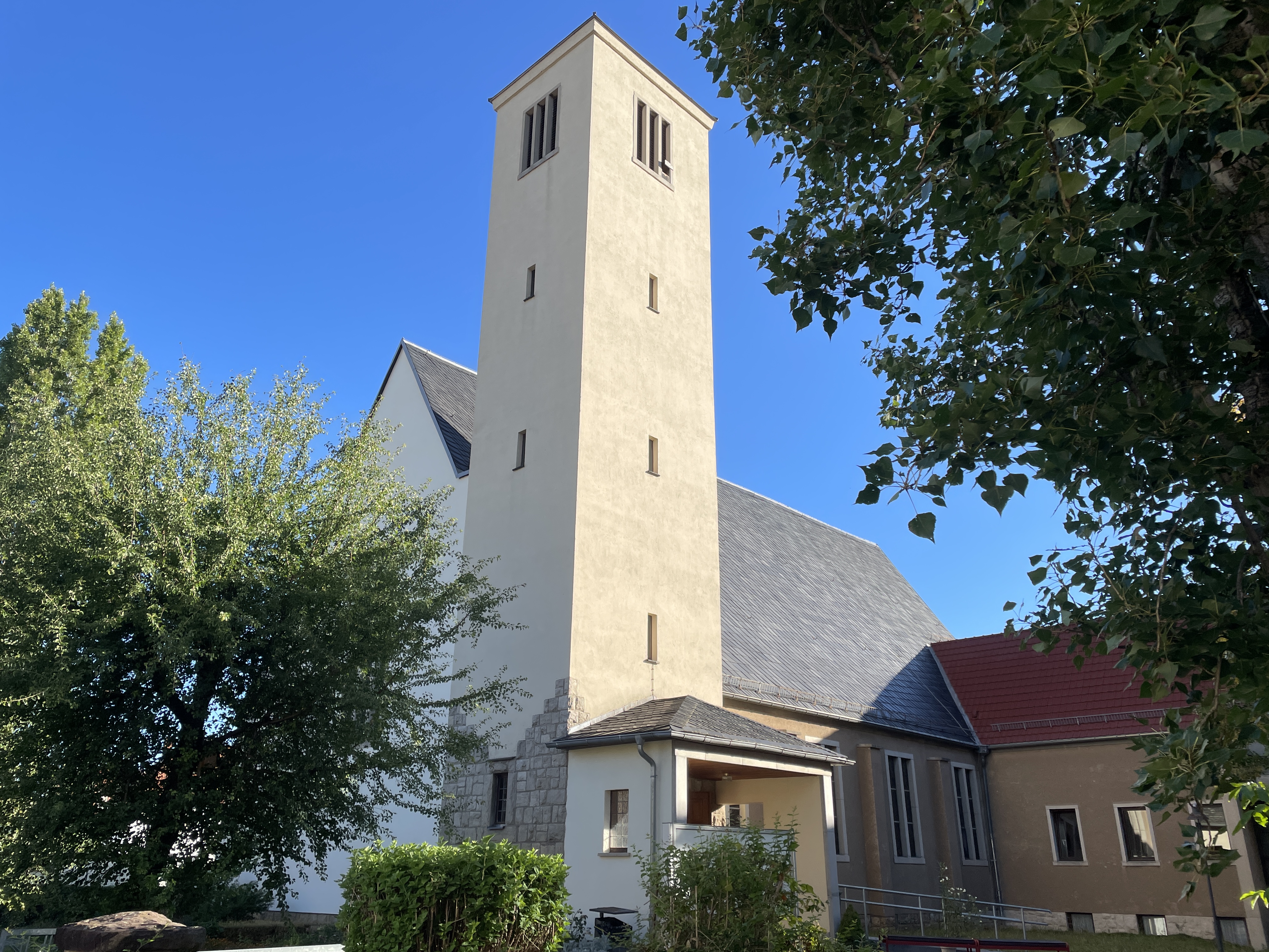 Kirchengebäude mit großem Betonturm im Vordergrund