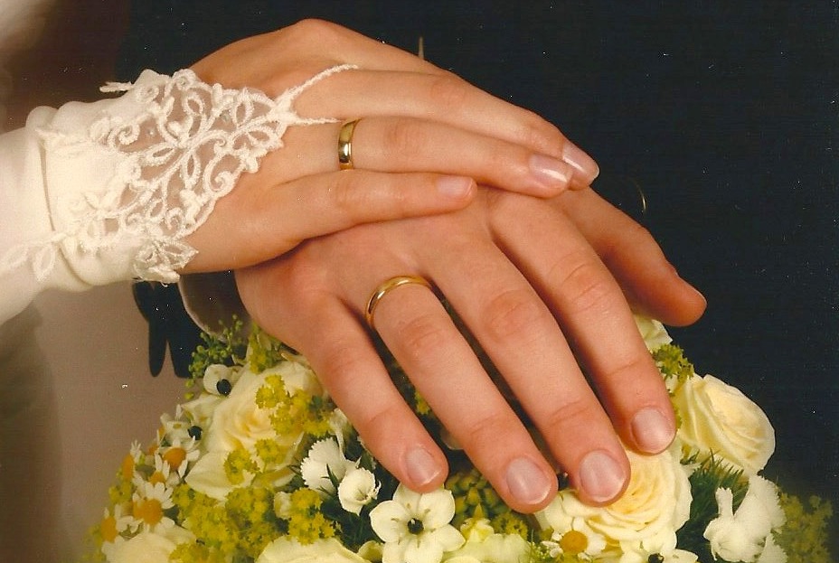 Hand eines Mannes und einer Frau mit Eheringen